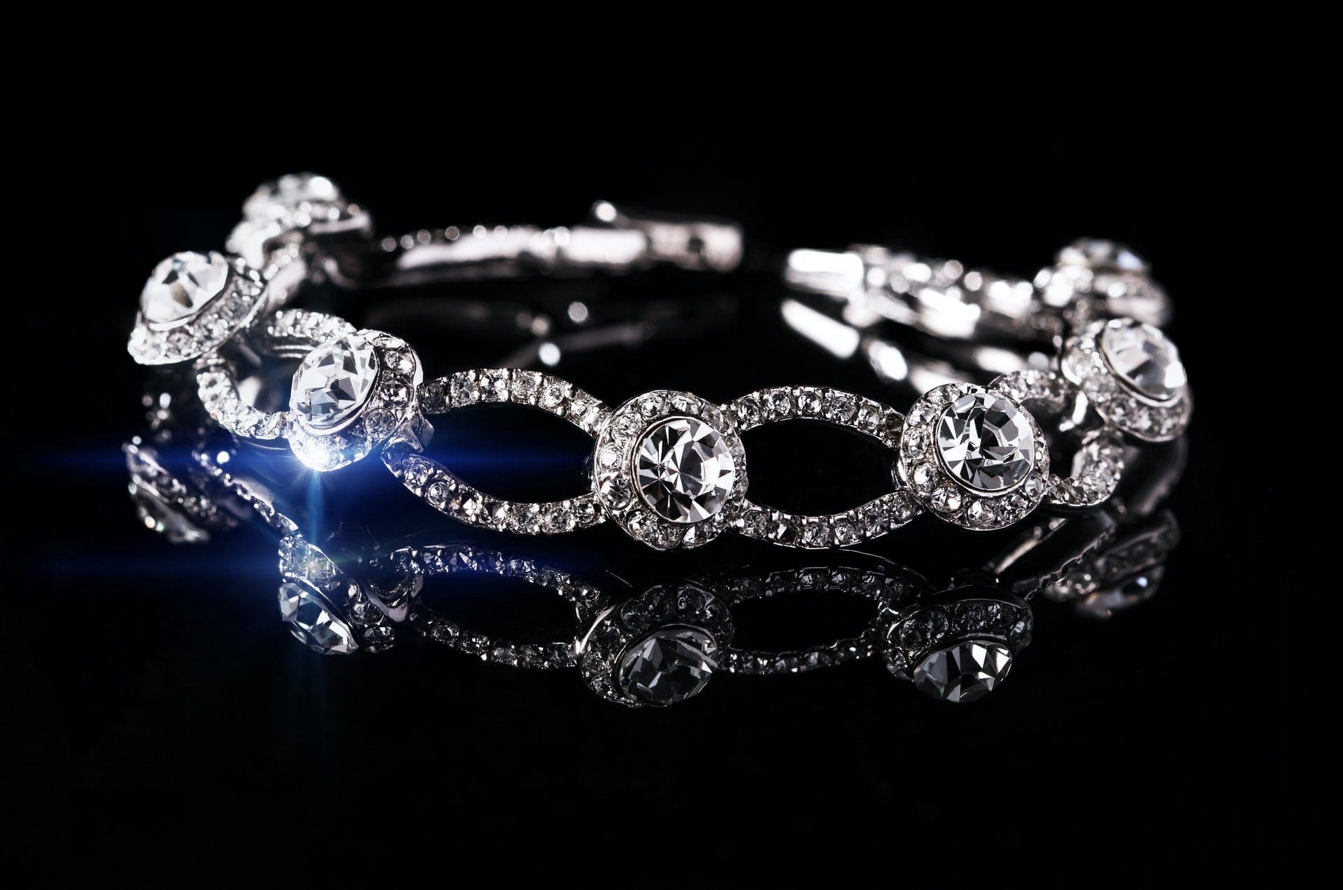 A sparkling diamond bracelet on a reflective black surface, showcasing its intricate design and brilliant gems.