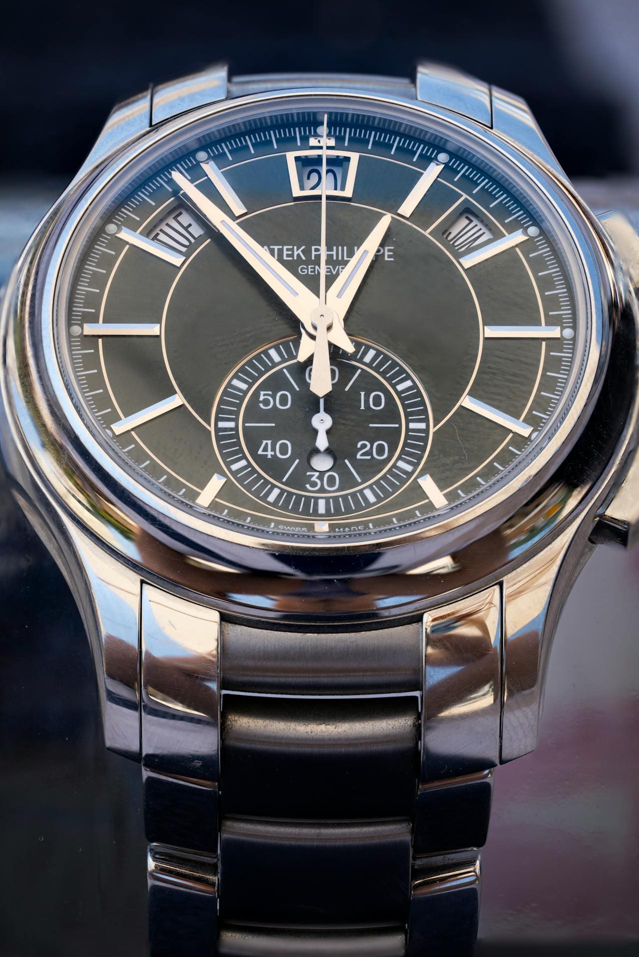 Close-up of a Patek Philippe watch with a dark dial, silver hands, and a chronograph sub-dial.