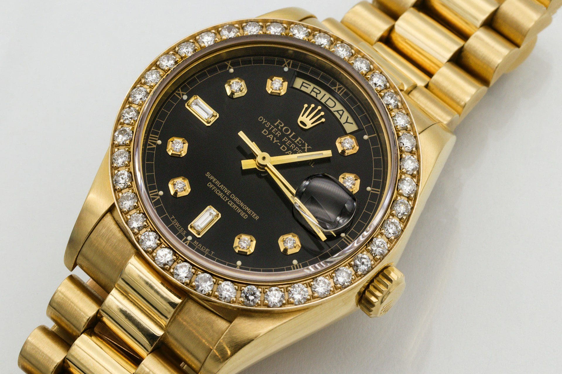 Close-up of a gold Rolex Day-Date watch with a black dial and diamond bezel, showcasing luxury and precision.