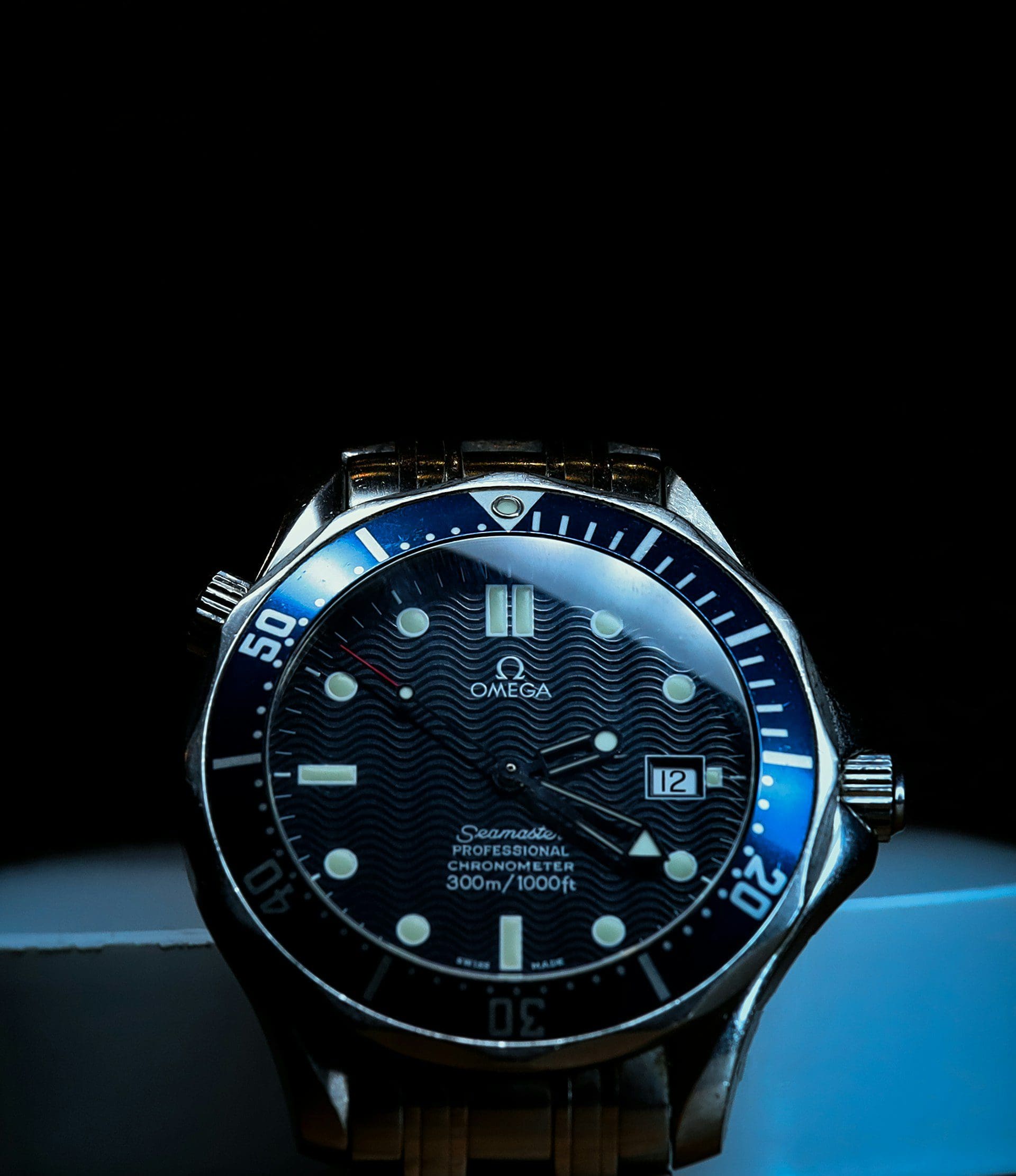Close-up of an Omega Seamaster Professional Chronometer watch with a blue bezel and black wave dial.