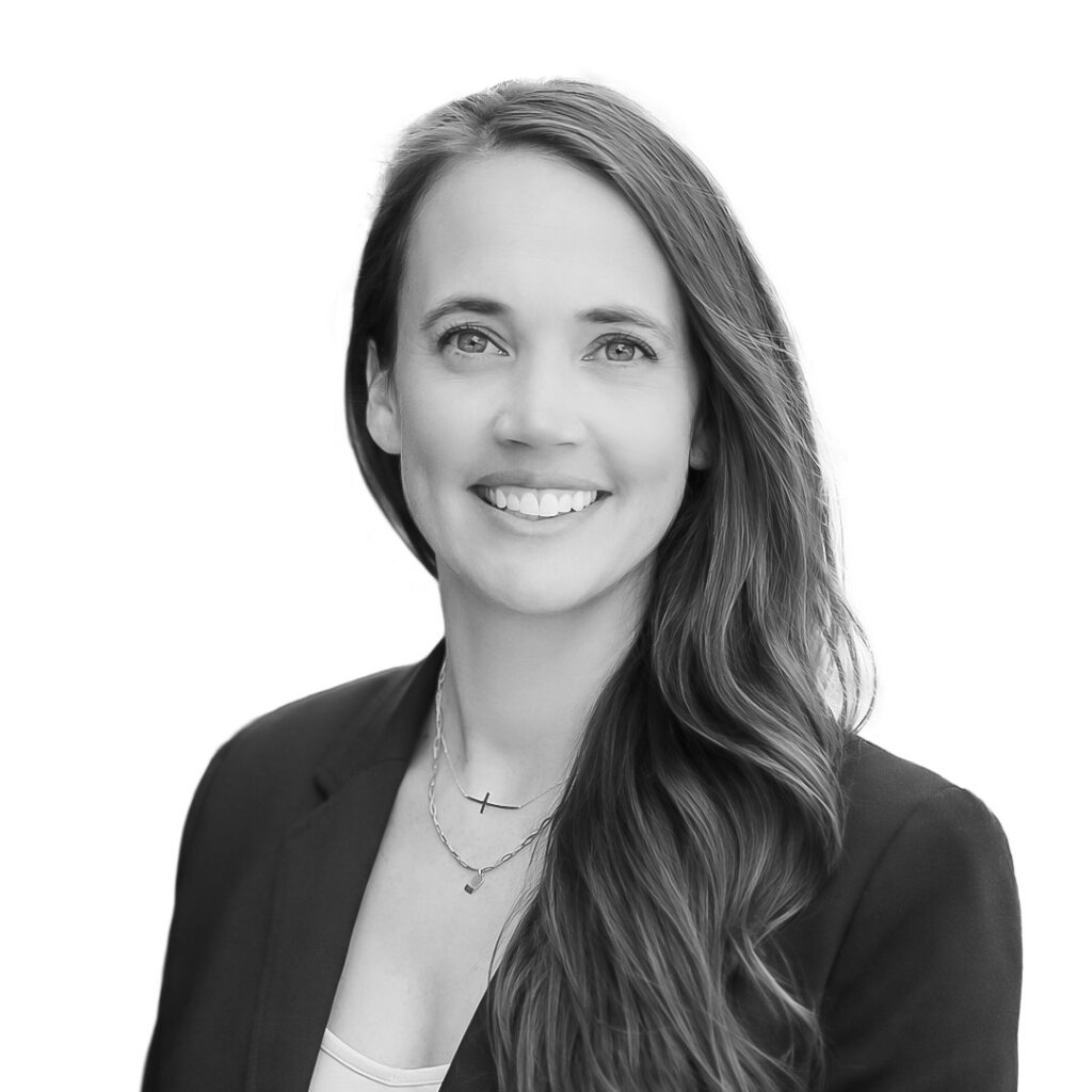 Professional headshot of a smiling woman with long wavy hair, wearing a dark blazer, facing the camera.